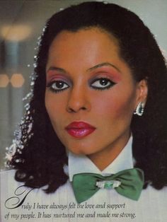 a woman with long black hair wearing a green bow tie and white shirt is looking at the camera