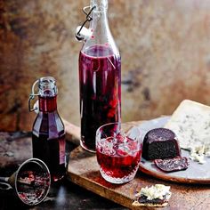 a bottle of wine and two glasses on a cutting board next to some cheeses