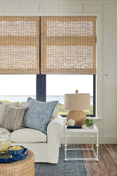 the living room is decorated with blue and white decor, including wicker shades on the windows