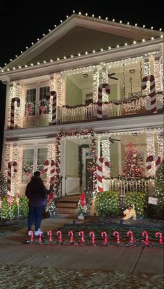 a woman standing in front of a house decorated with christmas lights and candy canes