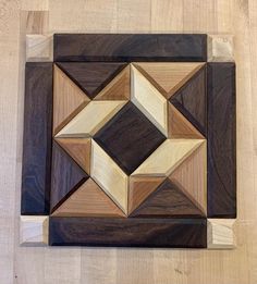 a square shaped wooden object on top of a hard wood flooring surface with several different colored squares in the center