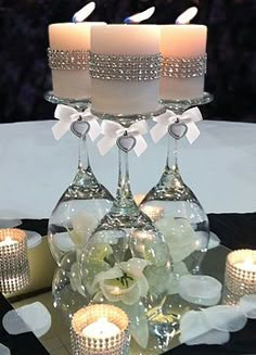 three candles are lit in front of two wine glasses on a table with white flowers