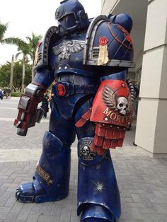 a giant blue and red robot standing on top of a brick sidewalk in front of a building