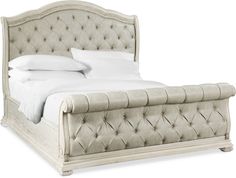 an upholstered bed with white linens and pillows