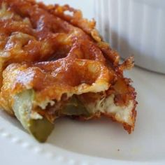 a close up of food on a plate near a cup with sauce in the background