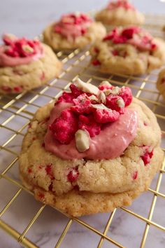 cookies with pink icing and white chocolate chips on a cooling rack