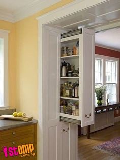 an open cabinet in the middle of a kitchen with yellow walls and white trim on the doors