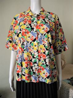 Beautiful Vintage short sleeve blouse from the 1980s. Comfortable cotton fabric with a vibrant summer floral pattern. Straight, boxy cut, wide sleeves, button down. Looks great with a pair of jeans and flatform sandals. BRAND: C&A ERA: 1980s COLOR: White, black, green, yellow, red, lilac FABRIC: 100% cotton SIZE: No size tag, fits best size M to small L (or S for a more oversized fit) - please check measurements below for reference MEASUREMENTS: Pit to pit 54cm, total length 60cm CONDITION: Spring Short Sleeve Shirt With Floral Print, Short Sleeve Shirt With Floral Print For Spring, Floral Print Short Sleeve Shirt For Spring, Retro Summer Blouse With Vintage Print, Vintage Multicolor Short Sleeve Shirt, Multicolor Floral Print Short Sleeve Shirt For Summer, Summer Multicolor Floral Print Short Sleeve Shirt, Spring Vintage Print Hawaiian Shirt With Short Sleeves, Vintage Multicolor Short Sleeve Tops