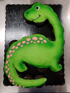 a green dinosaur cake sitting on top of a black plate