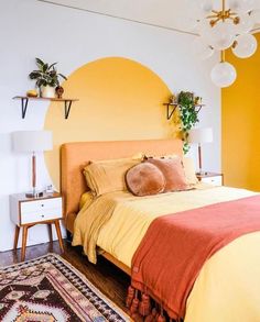 a bedroom with yellow walls and orange bedspread on top of the bed is decorated with potted plants