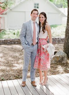 a man and woman standing next to each other on a wooden deck in front of a tree