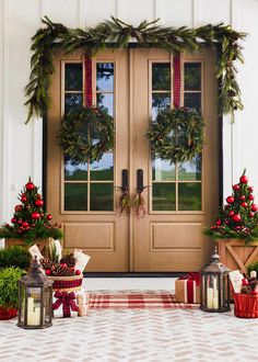 two christmas wreaths on the front door of a house