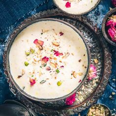 two bowls filled with food sitting on top of a blue cloth covered table next to spoons