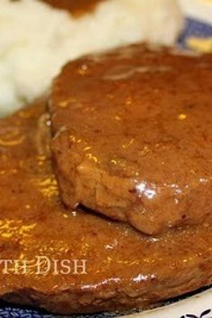 a close up of some meat on a plate with gravy and mashed potatoes