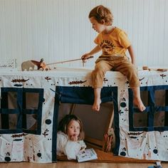 two young children sitting on top of a play tent