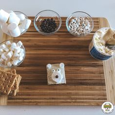 marshmallows, graham crackers and other treats are arranged on a cutting board