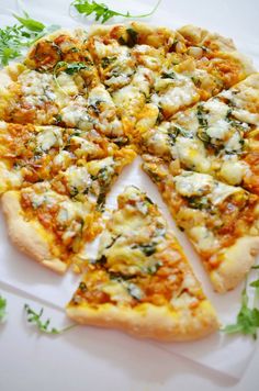 the pizza is cut into four pieces and has cheese, herbs, and other toppings on it