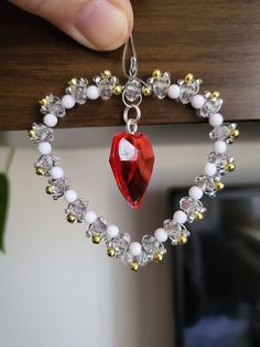 a hand holding a heart shaped necklace with beads