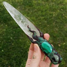 a person holding a green and black object in their left hand with grass in the background