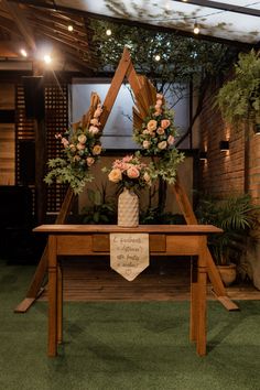 a wooden table topped with flowers and greenery