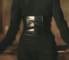 a woman wearing a black leather outfit and holding her hands out in front of her back