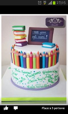 there is a cake that has many colored crayons on it and a chalkboard in the background