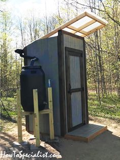 an outhouse in the woods with a water tank