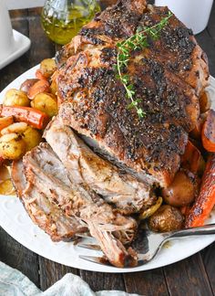 a white plate topped with meat, potatoes and carrots on top of a wooden table