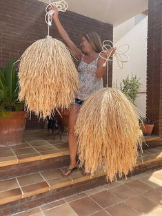 a woman is standing on the steps with two large straw balls in front of her