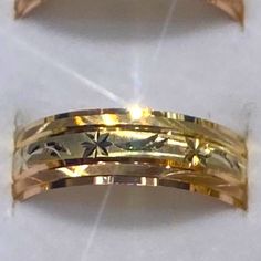 two gold wedding bands with flowers and leaves on them, set against a white background