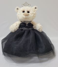 a white teddy bear wearing a black dress with a tiara on it's head