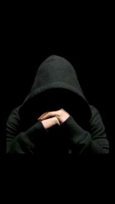 a person wearing a black hooded jacket and covering their face