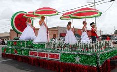 some people are riding in a float with watermelon umbrellas on the street