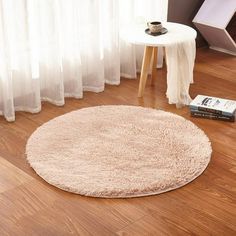 a round rug on the floor next to a table with a book and coffee cup