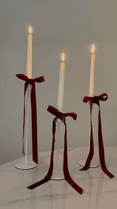 three white candles with red ribbon tied around them