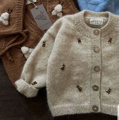 three sweaters are sitting on a table with tags attached to the top of them