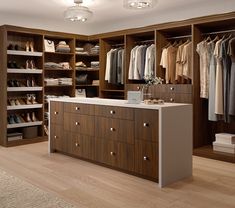 a large closet with lots of clothes and shoes on shelves next to a counter top