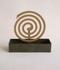 a wooden sculpture with a spiral design on it's base in front of a white wall