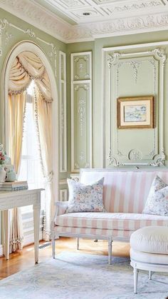 a living room with green walls and white furniture in the corner, along with a striped couch