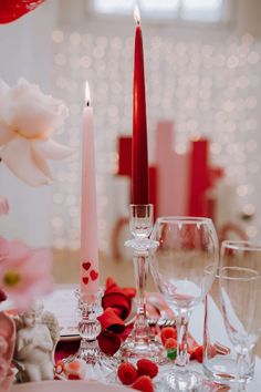 the table is set with two candles, wine glasses, and flowers on it for valentine's day