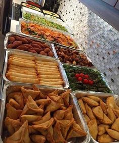 several trays of food are lined up on the counter in front of each other