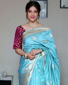 a woman in a blue and gold sari is standing with her hands on her hips