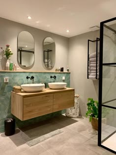 a bathroom with two sinks and mirrors on the wall next to each other in front of a shower