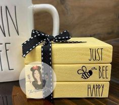 three yellow books with black bows are stacked on top of each other next to a coffee mug