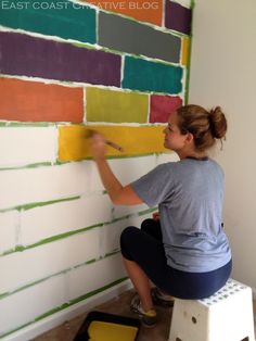 a woman is painting a wall with different colors