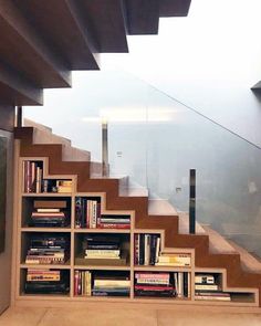 there is a book shelf with many books on it and stairs leading up to the second floor