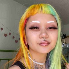 a woman with multi - colored hair and piercings on her nose is looking at the camera