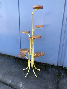 a yellow metal and wood stand with five wooden trays on it's sides