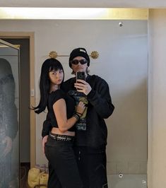 a man and woman standing in front of a mirror taking a selfie with their cell phone