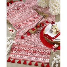 a red and white table cloth with tassels on it is laying on the floor